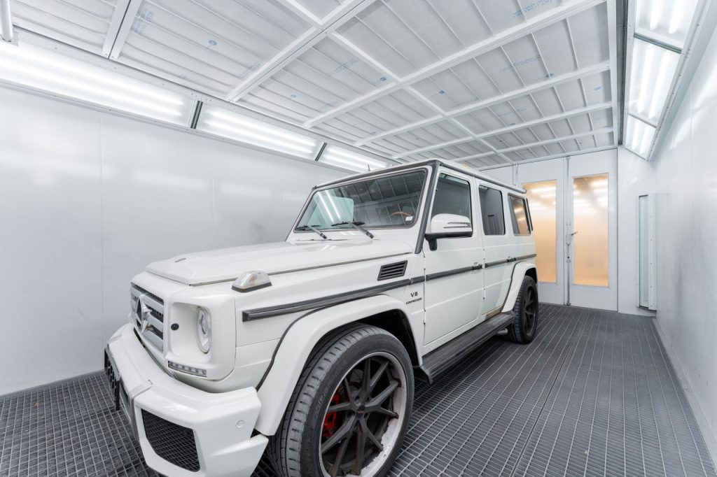 A white luxury SUV parked in a bright, modern indoor garage with industrial design.