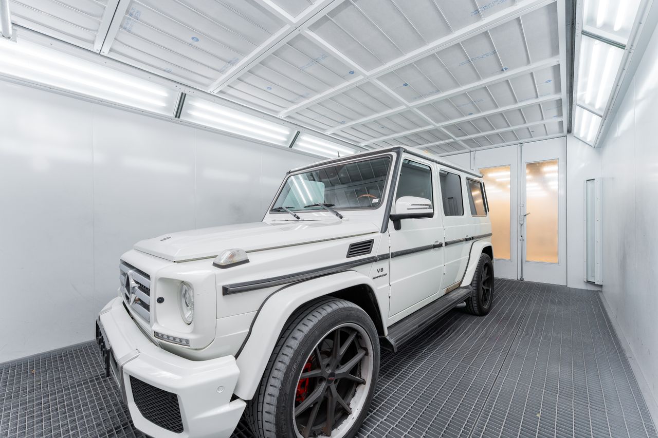 A white luxury SUV parked in a bright, modern indoor garage with industrial design.